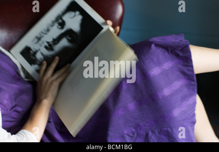 La donna a vestire la lettura di libro di poesie, vista ritagliata della sezione centrale, ad alto angolo di visione Foto Stock