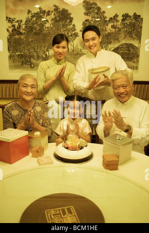 Tre generazioni la famiglia battendo le mani durante la festa di compleanno, sorridente in telecamera Foto Stock