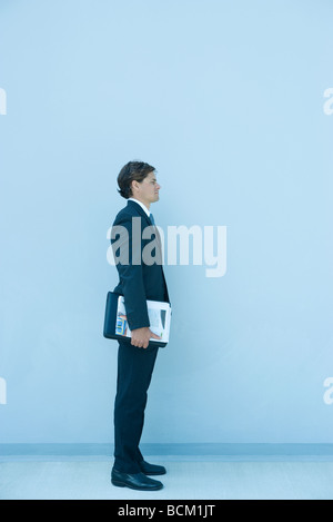 Businesman standing, legante di contenimento sotto braccio a piena lunghezza Foto Stock