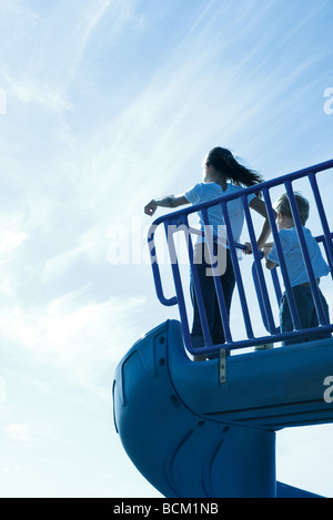 I bambini in piedi sul parco giochi diapositiva, basso angolo vista, vista posteriore Foto Stock