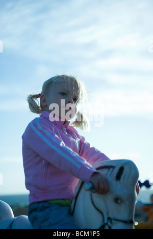 Ragazza seduta sul cavallo a dondolo, azienda gestisce, close-up Foto Stock