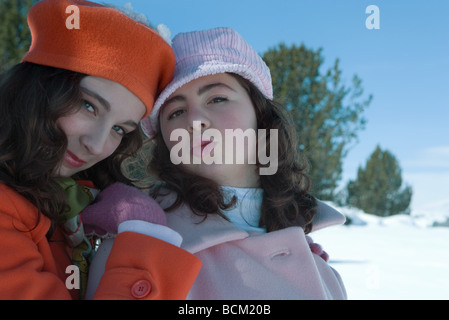 Due ragazze adolescenti vestito in abiti invernali, sia guardando alla telecamera, un raggrinzimento Foto Stock