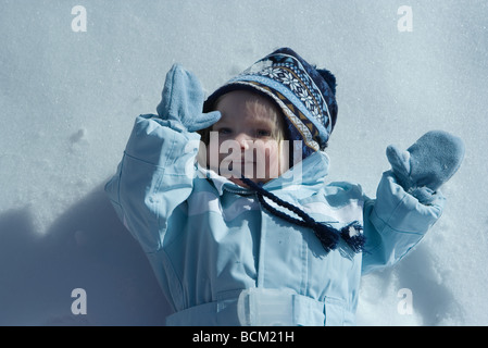 Il Toddler ragazza distesa sul retro nella neve, sorridente, ad alto angolo di visione Foto Stock