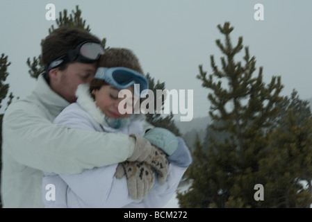 Coppia giovane abbracciando a occhi chiusi entrambi vestiti in abiti invernali Foto Stock