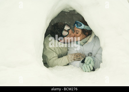 Coppia giovane baciare in igloo a occhi chiusi Foto Stock