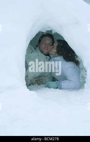 Coppia giovane baciare in igloo, uomo guardando la fotocamera Foto Stock