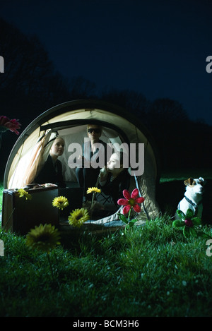 Femmina di business associates seduta nella tenda di notte, utilizzando un telefono su rete fissa, cane seduto accanto alla tenda Foto Stock