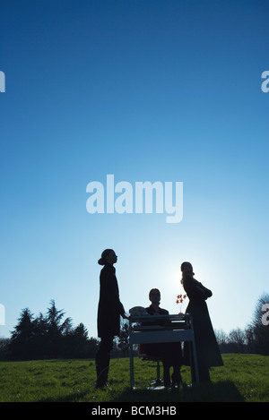 Tre donne al desk nel campo, silhouette Foto Stock