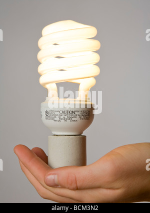 Mano che tiene una nuova energia efficiente compatto per lampade fluorescenti Foto Stock