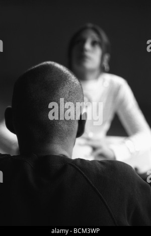 Due persone faccia a faccia, concentrarsi sull'uomo con la testa rasata in primo piano Foto Stock