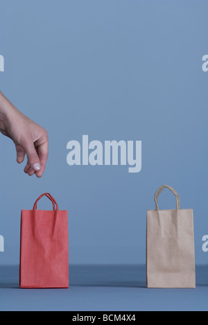 Due piccole buste regalo, donna di mano raggiungendo per la solitaria uno rosso Foto Stock