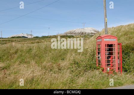 Cabina telefonica rossa abbandonata e troppo grande nel paesaggio Foto Stock