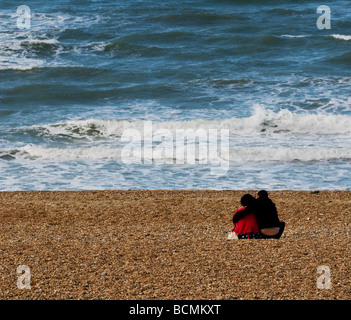 Un uomo e una donna seduta insieme sulla spiaggia di ciottoli a Brighton in Sussex. Foto di Gordon Scammell Foto Stock