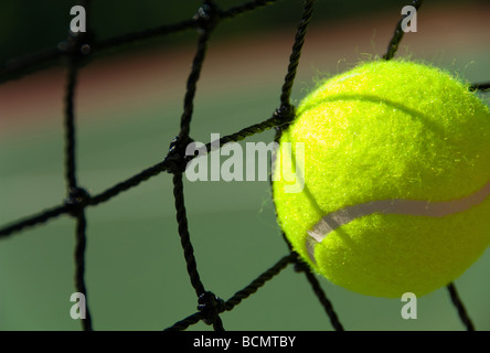 Luminoso giallo verdolino palla da tennis su dipinta di fresco corte di cemento Foto Stock