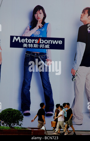 Persone walking pass billboard gigante del marchio di moda, Metersbonwe, Shanghai, Cina Foto Stock