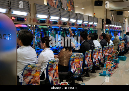 Le persone che giocano il popolare Pachinko pinball macchine per il gioco d'azzardo in Jumbo Pachinko parlor nel quartiere Shibuya di Tokyo Giappone Foto Stock