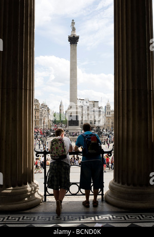 I turisti guardano verso la colonna di Nelson in Trafalgar Square e dai passaggi della National Gallery di Londra, Inghilterra. Foto Stock