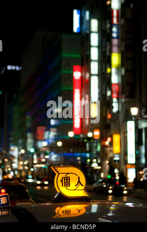 Taxi segno pubblicità con schermi in background nel quartiere di Ginza Tokyo Giappone Foto Stock