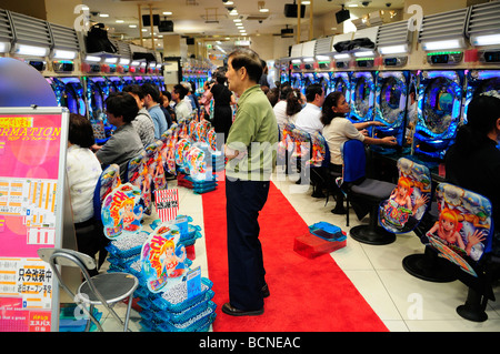 Le persone che giocano il popolare Pachinko pinball macchine per il gioco d'azzardo in Jumbo Pachinko parlor nel quartiere Shibuya di Tokyo Giappone Foto Stock