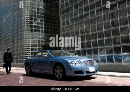 Un uomo giapponese passano da una Bentley auto di fronte della Maison Hermes edificio nel quartiere di Ginza Tokyo Giappone Foto Stock