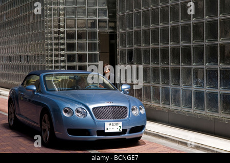 Una donna giapponese parla con un autista in una Bentley auto di fronte della Maison Hermes edificio nel quartiere di Ginza Tokyo Giappone
