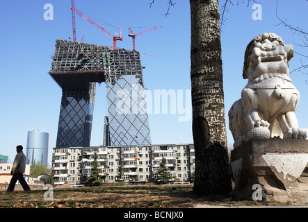 Man walking pass la torre TVCC ancora in costruzione, Pechino, Cina Foto Stock