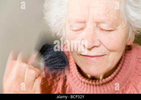 Frau in ihren Siebzigern lässt sich im Gesicht pudern Foto Stock