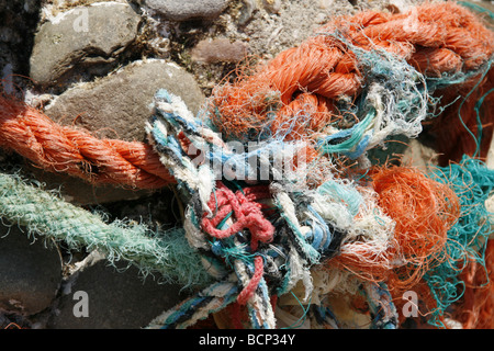 Dettaglio di un fascio di funi aggrovigliati lavato fino sulla spiaggia rocciosa Foto Stock