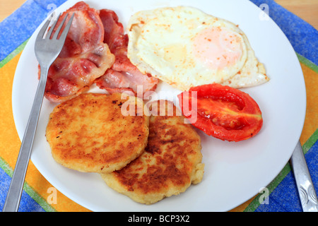 Un fritto colazione a base di frittelle di patate uova pancetta e pomodoro Foto Stock