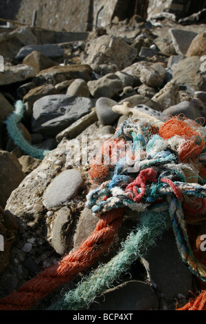 Dettaglio di un fascio di funi aggrovigliati lavato fino sulla spiaggia rocciosa Foto Stock