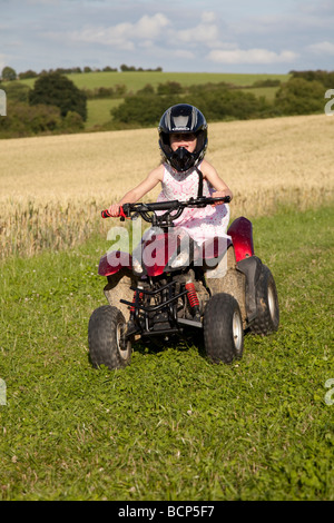 Giovane ragazza piccola di equitazione quad bike farm field Costwolds REGNO UNITO Foto Stock