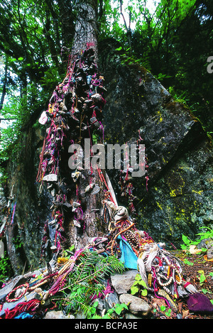 Pebble legata con filo colorato, hada e grani di preghiera ammucchiati sotto un albero sacro per la benedizione di Dio dai pellegrini, Yubeng Foto Stock