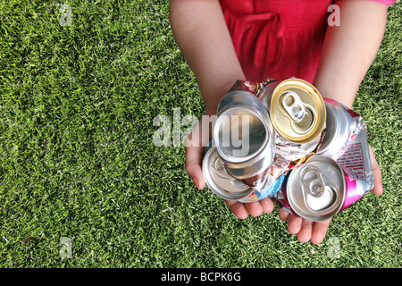 Le lattine di alluminio schiacciato per il riciclaggio in un bambino le mani Foto Stock