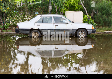 Una vettura parcheggiata su una strada allagata in Vietnam Foto Stock