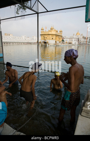 Gli uomini di religione sikh bagnarsi nelle acque - il Sarovar (serbatoio acqua) -intorno al tempio d'Oro (Sri Harmandir Sahib) Amritsar. Il Punjab. India Foto Stock