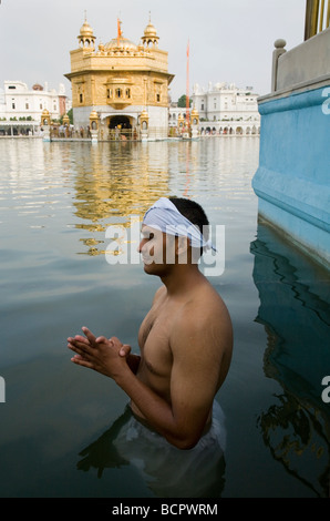 La religione sikh uomo balneazioni in acque - il Sarovar (serbatoio acqua) -intorno al tempio d'Oro (Sri Harmandir Sahib) Amritsar. Il Punjab. India Foto Stock