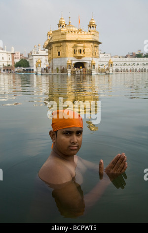 La religione sikh uomo balneazioni in acque - il Sarovar (serbatoio acqua) -intorno al tempio d'Oro (Sri Harmandir Sahib) Amritsar. Il Punjab. India Foto Stock