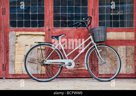 Una bicicletta appoggiata contro una parete in un villaggio del Vietnam centrale Foto Stock