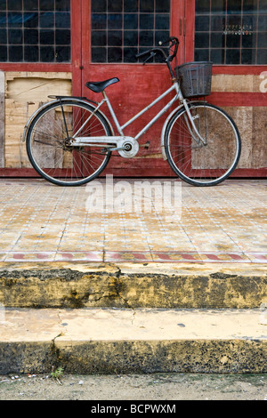 Una bicicletta appoggiata contro una parete in un villaggio del Vietnam centrale Foto Stock