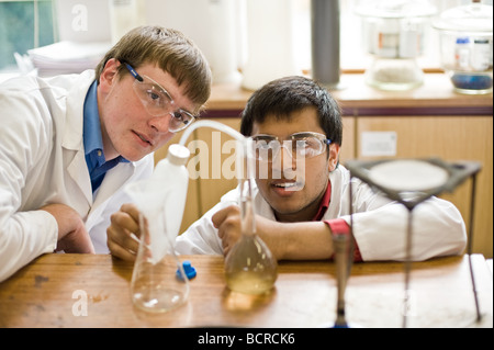 UK School England Grammar School Education - due studenti maschi che versano liquidi in un esperimento in un laboratorio di scienze scolastiche. Foto Stock