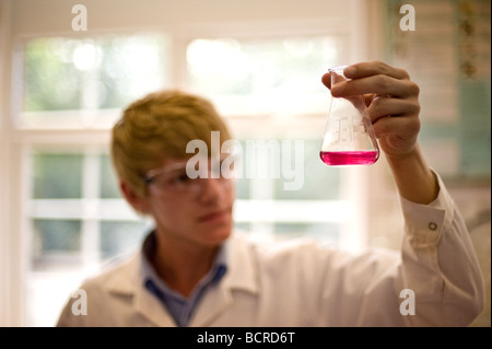 UK School England Grammar School Education - UN giovane studente di sesso maschile che esamina un pallone di liquido colorato in una lezione di scienza scolastica. Foto Stock