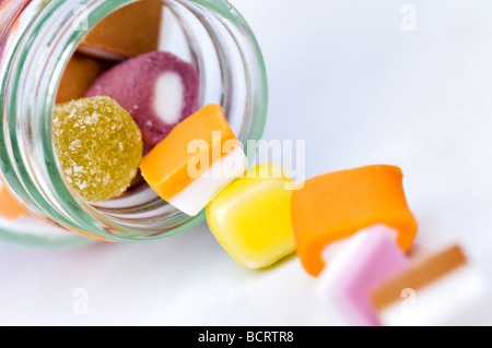 Close up di dolly miscela dolci tumbling fuori del vasetto di vetro contro uno sfondo bianco Foto Stock