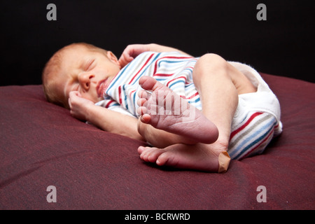 Sleeping neonato ragazzo fotografato su un nero di sfondo per studio. Foto Stock