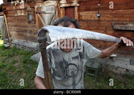 Un contadino rumeno pone con la sua falce nella parte anteriore della fotocamera. Foto Stock