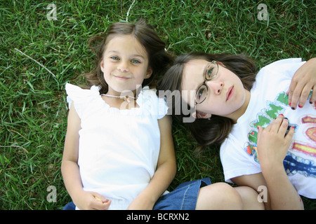 Ritratto di due sorelle sdraiati sull'erba Foto Stock