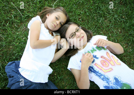 Ritratto di due sorelle sdraiati sull'erba Foto Stock