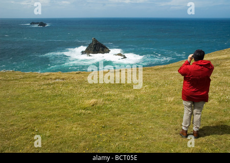 Il camminatore femmina birdwatching sul sud-ovest sentiero costiero a testa di Dinas, North Cornwall Foto Stock