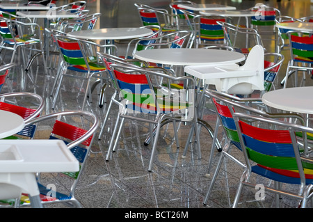Colore sedili in metallo e in plastica bianca su tabelle il brillare il pavimento sono in cafe Foto Stock