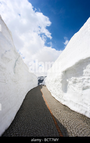 Pavimentazione in ciottoli della vecchia strada del San Gottardo tra alti muri di neve, Svizzera, Europa Foto Stock