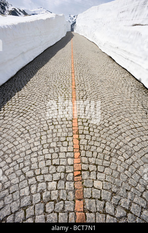 Pavimentazione in ciottoli della vecchia strada del San Gottardo tra alti muri di neve, Svizzera, Europa Foto Stock